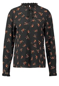 Blouse noire à manches longues avec motif florale orange et beige, col et poignets volantés, et un nœud noué au niveau de l'encolure.