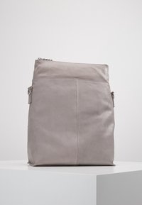 Šedá kožená taška s hladkým povrchem, obdélníkovým tvarem a horním zipovým uzávěrem. Obsahuje boční páčku a minimální detaily šití.