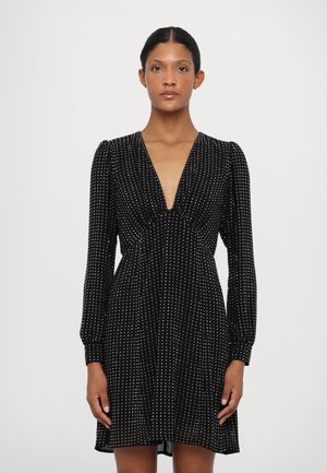 Black dress featuring a deep V-neck, long sleeves, and a fitted waist, adorned with white polka dots throughout the fabric.