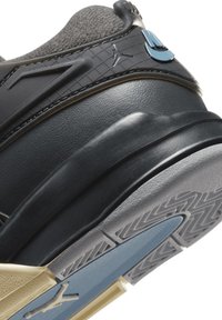 Sneaker nera con tomaia in pelle testurizzata, colletto in tessuto grigio, dettagli stampati e suola in gomma con un elemento blu.