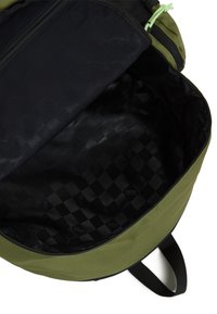Interior de mochila verde con un bolsillo de malla y forro texturizado negro con un patrón de diamantes. Cierre con cremallera y bordes reforzados.