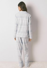 Pigiama azzurro chiaro con maniche lunghe e pantaloni, caratterizzato da un motivo geometrico. Realizzato in tessuto morbido con una vestibilità comoda e cintura elastica.
