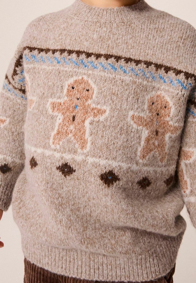 Pull tricoté beige avec motifs de bonhomme en pain d'épice sur la poitrine et les manches avec des motifs décoratifs bleus et bruns.