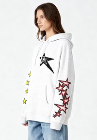 Felpa con cappuccio grigio chiaro in misto cotone, con una grande stella nera sul davanti e stelle colorate (gialle e rosse) lungo le maniche.