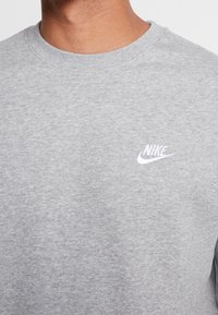 Sudadera gris de mezcla de algodón. Presenta un cuello redondo, puños de canalé y un pequeño logo de Nike bordado en el pecho.
