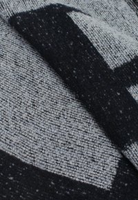 Tessuto intrecciato con un motivo geometrico in grigio e nero, che presenta una superficie testurizzata con densità di filo variabili.