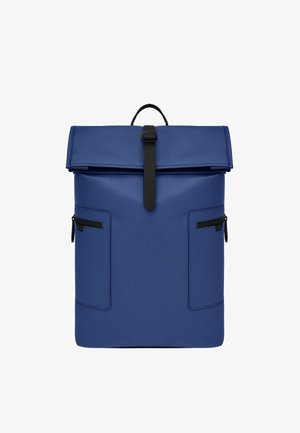 Sac à dos bleu à rabat enroulable avec fermeture à sangle noire, deux poches latérales zippées et une poignée supérieure.
