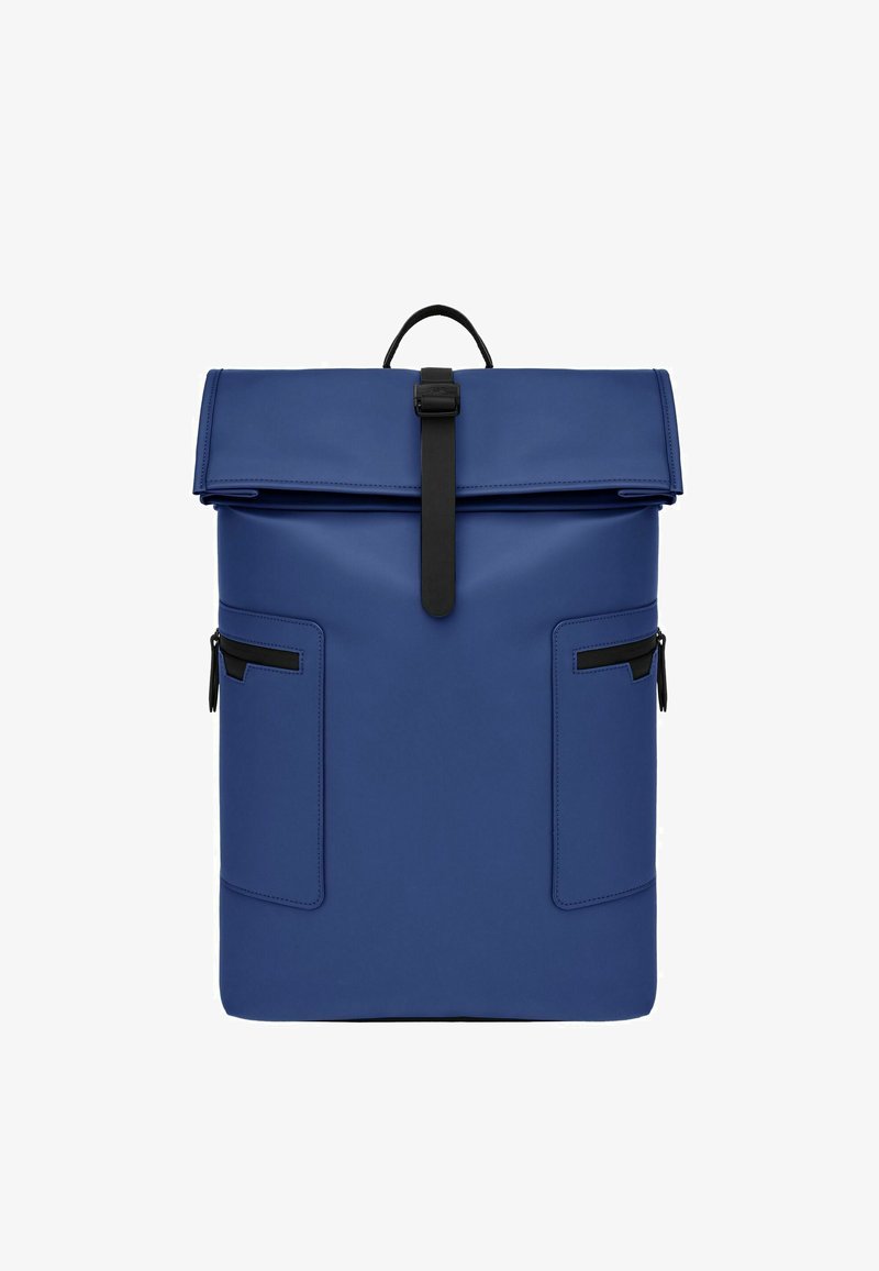 Sac à dos bleu à rabat enroulable avec fermeture à sangle noire, deux poches latérales zippées et une poignée supérieure.