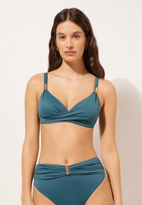 Teal tvådelad bikiniuppsättning med en twist-fram-front, justerbara axelremmar och guldfärgade detaljer på remmar och midjeband, slät struktur.