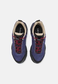Zapatillas de ante moradas con suelas de goma negra. Presentan cordones elásticos burdeos y un forro interior de color beige claro. Detalles de superficie texturizada visibles.