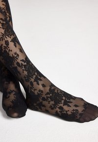 Sorte lette strømpebukser med blomstermønster i blonde, der har en glat tekstur og en semi-transparent finish. Ankellængde med forstærket tå.