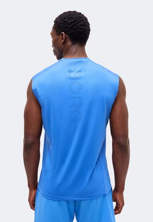 Mężczyzna widziany od tyłu, ubrany w niebieską sportową koszulkę bez rękawów i spodenki z perforowanym napisem "BORG" na plecach koszulki.