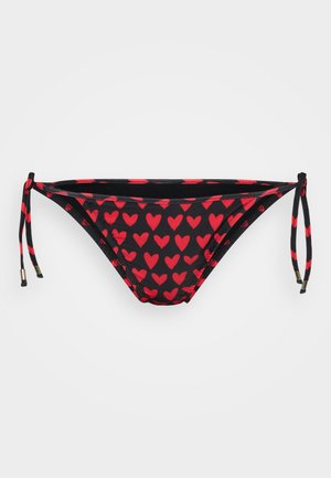 Bas de bikini noir avec un motif de cœurs rouges. Dispose de côtés à liens ajustables avec de petits accents en métal doré. Texture lisse.