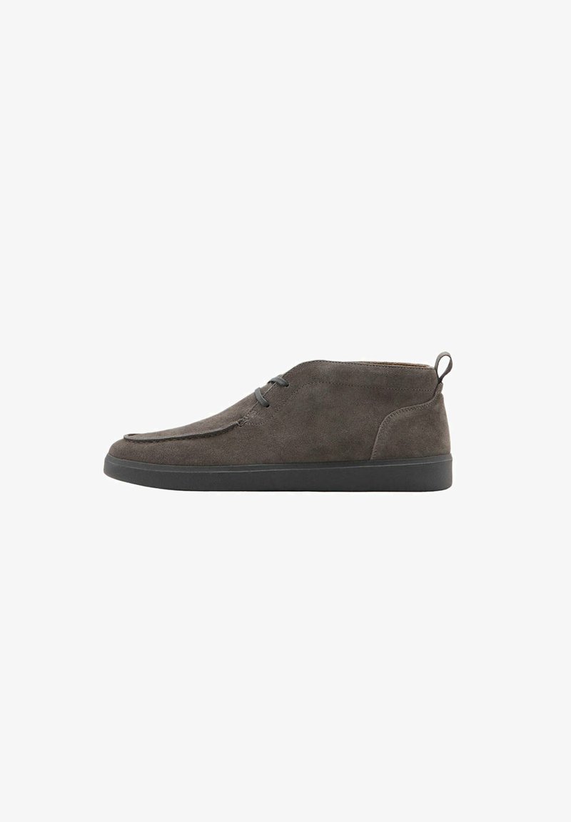 Chaussure décontractée à la cheville en suède gris foncé avec semelle en caoutchouc noire et deux œillets pour lacets, vue de profil sur fond blanc.