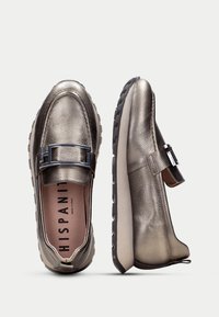 Metalen bronzen loafers met een gestructureerde leren bovenkant, zwarte gespaccent, en een comfortabel dempend zool. Gemaakt in Spanje.
