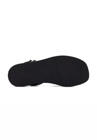 Black shoe sole with a textured surface, rounded shape, and a smooth upper edge. It features a flat design for comfort and stability.
