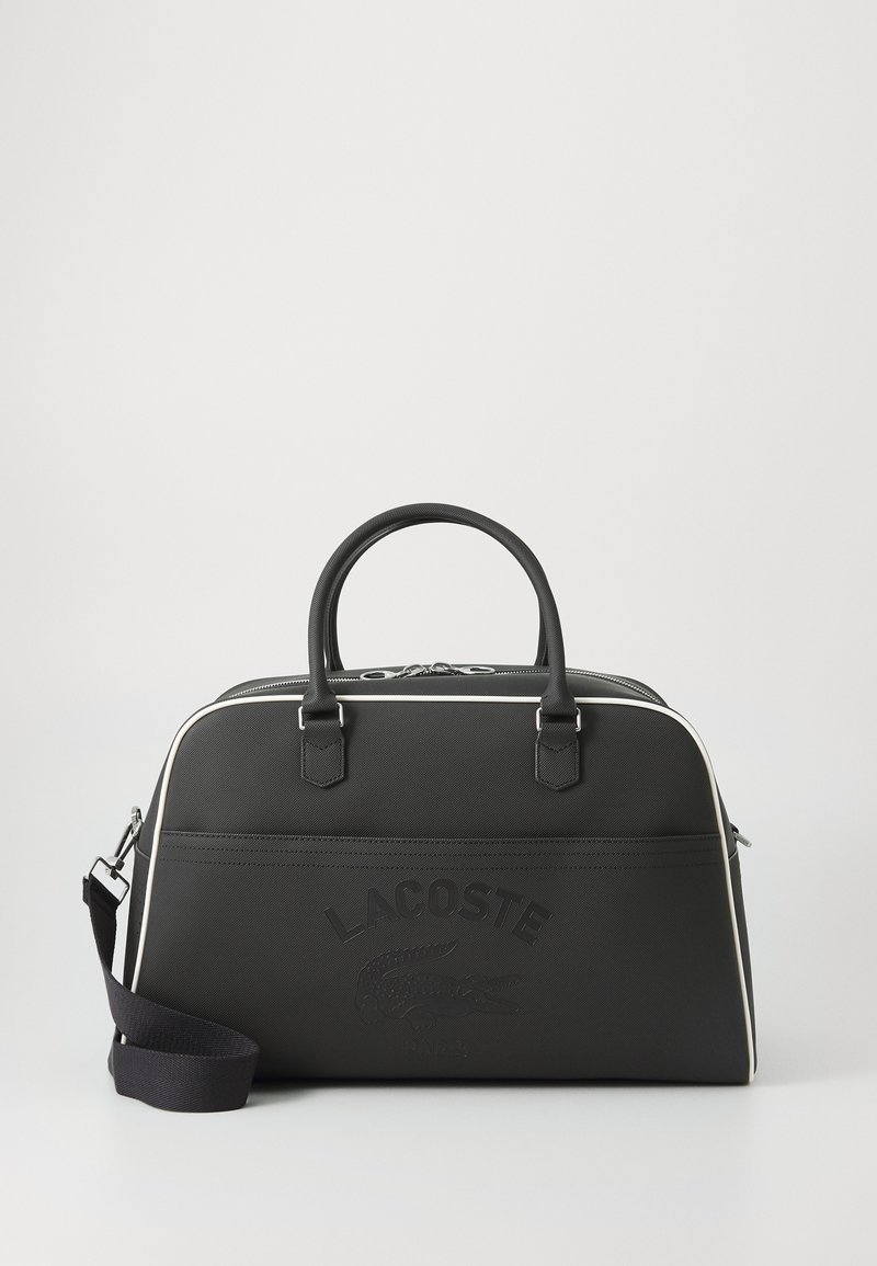 Borsa a tracolla nera realizzata in materiale testurizzato con una finitura liscia. Presenta logo impresso, dettagli bianchi, manici doppi e una tracolla regolabile.