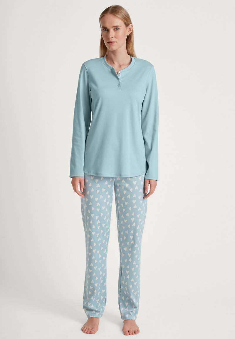 Lichtblauw lange mouwen pyjamajack met een ronde kraag en drie knopen, gecombineerd met lichtblauwe pantalons met een wit hartpatroon.