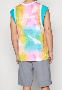 Jersey atlético sin mangas de varios colores con textura de malla, que presenta un degradado de rosa, azul, amarillo y verde. Con cuello blanco.