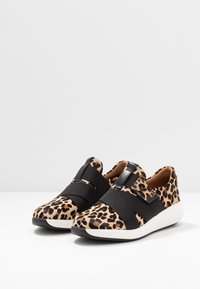 Leopardprint slip-on sko med sorte elastiske stropper og en hvid sål. Blødt tekstureret overdel med en afrundet tå og let forhøjelse.