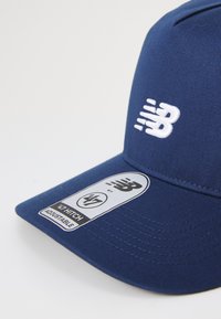 Gorra azul con un diseño estructurado, hecha de tela, que cuenta con una correa ajustable y un logo bordado en blanco en la parte frontal.