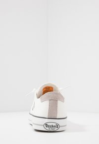 Weiße Leinenschuhe mit einem grauen Wildleder-Fersenpatch, Schnürdesign, Gummisohle und Logodetails an der Seite und Ferse.