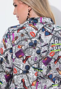 Camicia bianca con una stampa colorata in stile fumetto che presenta scarpe, occhiali da sole, borse e rossetto. Materiale liscio; design con colletto.