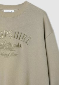 Oliwkowy sweter z prążkowanym okrągłym dekoltem, z tłoczonym napisem "HAMPSHIRE" oraz grafiką domu i drzew.