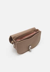 Læder skuldertaske i beige med en tekstureret overflade, der har en magnetisk lukning og en indvendig lomme med lynlås.