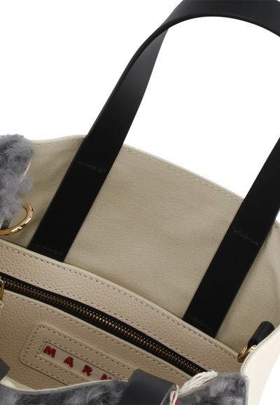 Borsa a tracolla in pelle beige con manici neri, caratterizzata da un accento in pelliccia grigia. L'interno include una tasca con zip e hardware dorato.