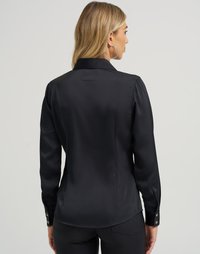 Blusa preta de mangas longas com um acabamento suave em satin, colarinho clássico, punhos com botões e um corte ajustado. Apresenta um detalhe na pala das costas.