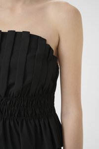 Svart stroppeløs topp med vertikale folder, elastisk smocking i midjen og en glatt tekstur med en tettsittende silhuett.