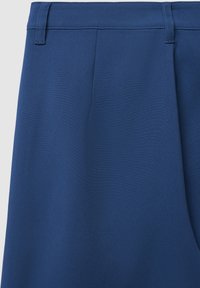 Blaue Hosen mit glatter Textur, flachem Frontbereich, dezenten Falten und einem taillierten Bund ohne sichtbare Beschläge.