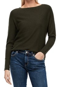 Maglione verde oliva con texture, scollatura ampia e maniche lunghe con dettagli di bottoni ai polsini, abbinato a jeans in denim blu.