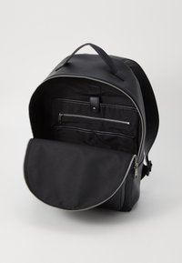 Black backpack with smooth leather exterior, zippered closure, and interior compartments. Minimalist design, fabric-lined inside.