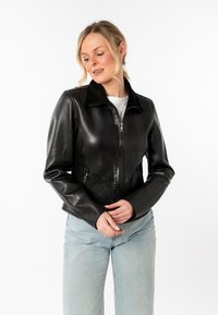 Zwarte leren jas met een gladde textuur, ritssluiting aan de voorkant en een kraagdesign. Getailleerde stijl met lange mouwen en subtiele stikdetails.