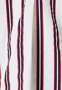 Il tessuto a strisce presenta linee verticali in rosso, blu navy e bianco. La trama appare liscia con una qualità leggera e ariosa.