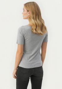 Grå t-shirt med korte ærmer lavet af blødt bomuld med en tætsiddende pasform og rund halsudskæring, parret med mørke jeans. Glat tekstur.