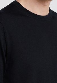 Svart stickad tröja med rund halsringning, mjuk textur och korta ärmar. Har en enkel, klassisk design utan ytterligare dekorationer.