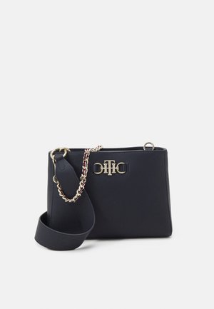 Sac à main bleu marine en matière texturée, avec des finitions en métal doré, un accent logo, et une bandoulière amovible ornée d'une chaîne décorative.