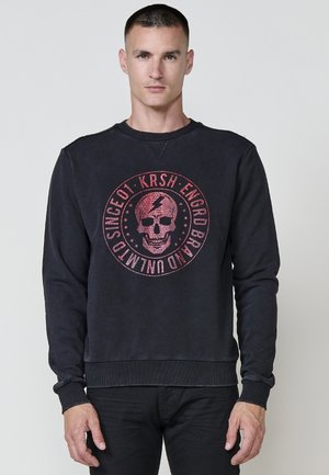 Sudadera negra con un gráfico de calavera roja redonda en el centro, puños y dobladillo acanalados, con una textura vintage desgastada y cuello redondo.