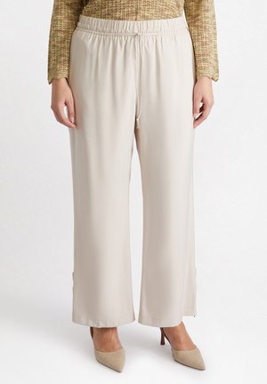 Beige wijdvallende broek gemaakt van een gladde stof met een elastische tailleband, voorzien van een trekkoord en subtiele zijsplitsingen aan de zoom.