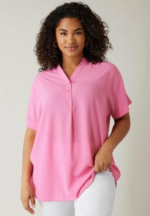 Pink short-sleeve top with a textured pattern, V-neckline, three-button placket, and a loose fit, paired with white pants.