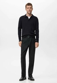 Černý pletený polo svetr, černé kalhoty rovného střihu a černé boty. Jednoduchý design s límečkem a strukturovanou tkaninou.