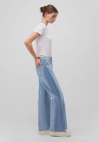 Light blue wide-leg jeans made of denim, featuring a high waist and vertical seam detailing, paired with a plain white short-sleeve t-shirt.