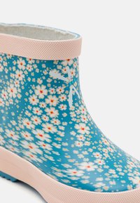 Kék gumicsizma virágmintával, kis fehér virágokkal és narancssárga középpel. Rózsaszín textúrázott gumi felső rész. Könnyű kialakítás.
