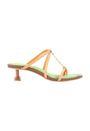 Sandale à bout ouvert avec petit talon en bois, fines lanières en cuir beige, détail chaîne dorée et semelle verte sur fond blanc.