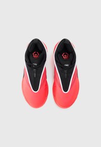 Une paire de baskets montantes rouges et noires avec fermeture éclair à l'avant et languettes de tirage, présentée vue de dessus sur un fond blanc.