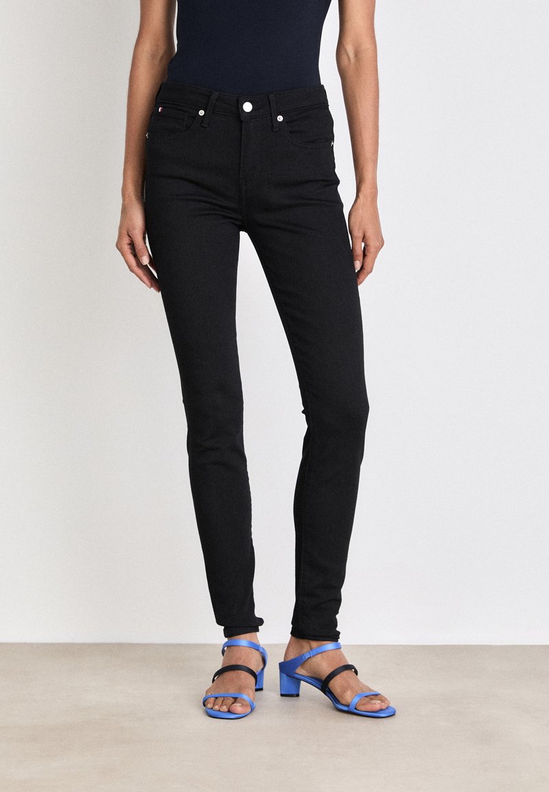 Sorte høytlivsjeans laget av denim, med klassisk fem-lommersdesign og små metalldetaljer, kombinert med blå hæl-sandaler.