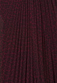 Tissu bordeaux à motif léopard noir, avec des plis verticaux créant texture et profondeur.